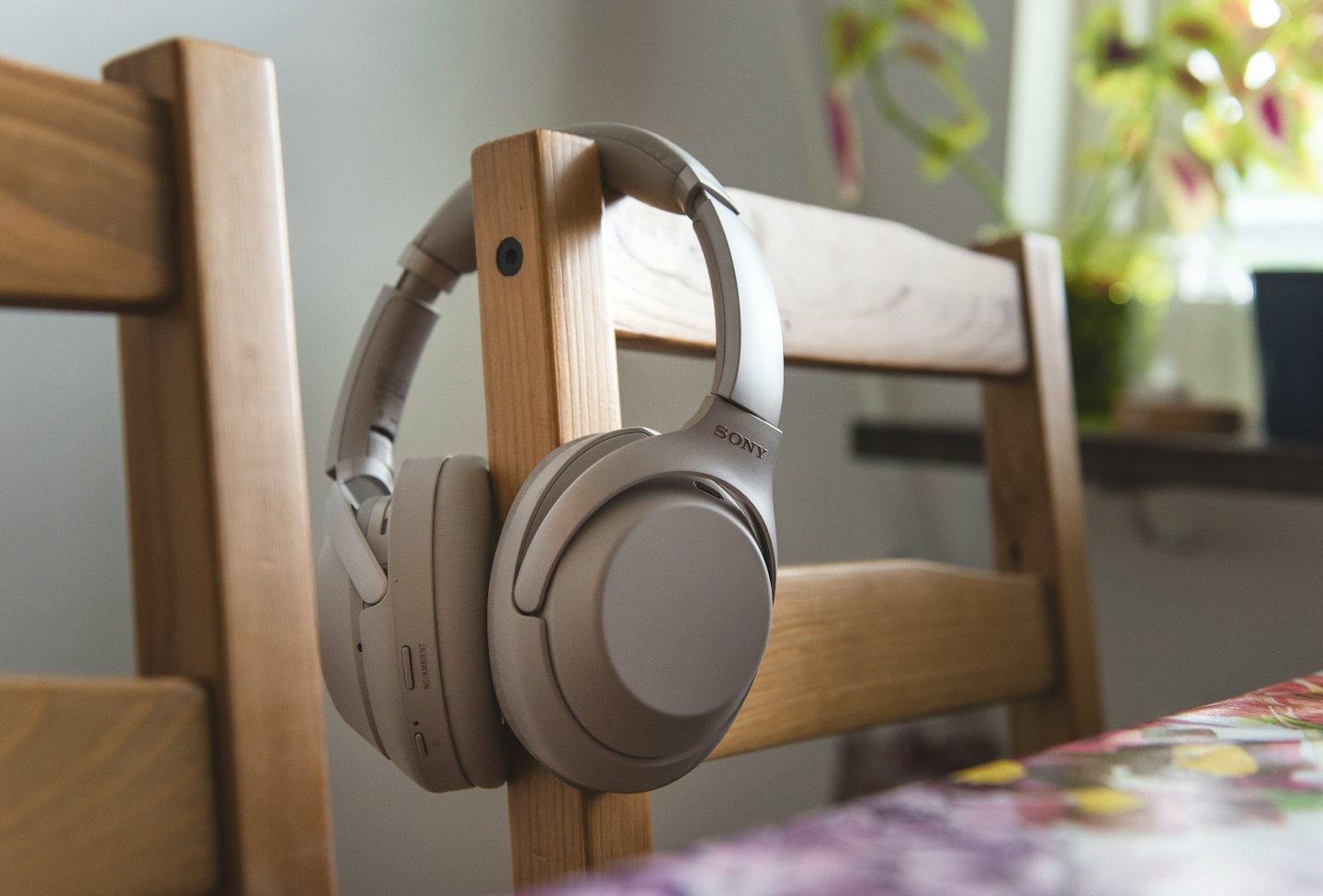 Beige headphones hanging on a wooden dining chair.